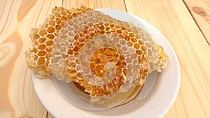 Honey dripping from honey dipper on honeycomb, over yellow background. slow motion