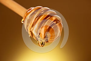 Honey dripping from honey dipper isolated on yellow