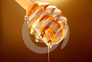 Honey dripping from honey dipper isolated on yellow