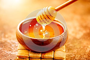 Honey dripping from honey dipper in wooden bowl.  Close-up. Healthy organic Thick honey dipping from the wooden honey spoon