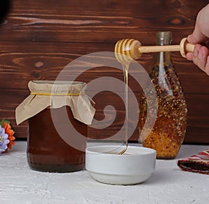 Honey dripping from honey dipper in wooden bowl. Close-up. Healthy organic Thick honey dipping from the wooden honey spoon, closeu