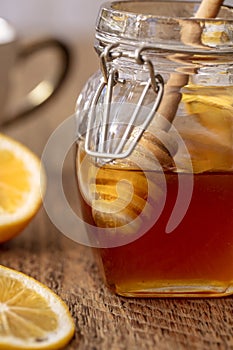Honey dripping into the jar with lemon slices on a wood table top