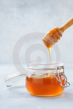 Honey dripping in a jar from wooden dipper