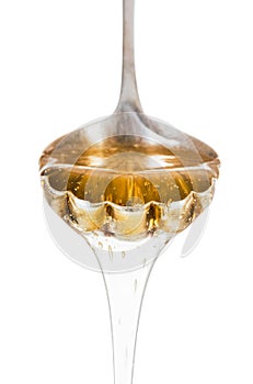 Honey dripping from silver spoon isolated on white