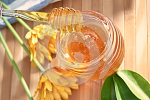 Honey dripping from a spoon of honey on bamboo wood