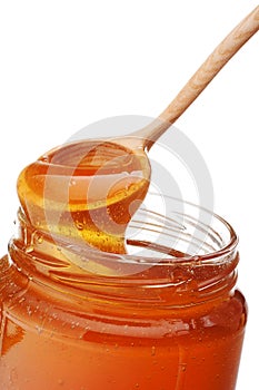 Honey dripping from a wooden honey dipper isolated on white back