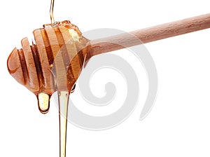 Honey dripping from a wooden honey dipper isolated on white back