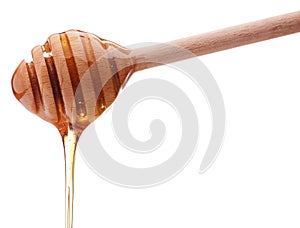 Honey dripping from a wooden honey dipper isolated on white back