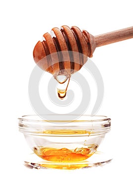 Honey dripping from a wooden honey dipper isolated on white back