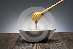 Honey drips from the spoon into a white bowl