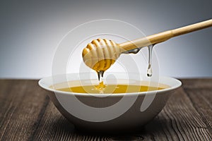 Honey drips from the spoon into a white bowl