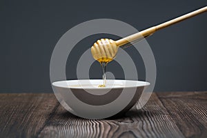 Honey drips from the spoon into a white bowl