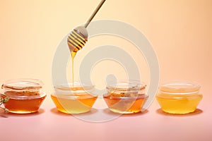 Honey drizzling from a wooden dipper into a glass bowl , different honey textures and hues.