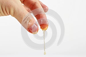 Honey flows from the fingers on white background