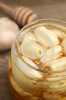 Honey with garlic in glass jar on table, closeup