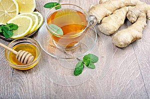 Honey, ginger, lemon and cup of tea on the wooden table. cold and flu remedy. close up.