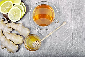 Honey, ginger, lemon and cup of tea on the wooden table. cold and flu remedy. close up.