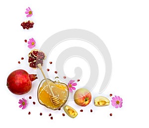 Honey in glass bowl, red apples, garnets, wooden honey dipper, pink flowers on a white background with space for text. Top view,