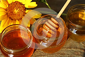 Honey in a glass jar with flowers on the wooden floor.