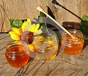 Honey in a glass jar with flowers on the wooden floor.