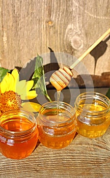 Honey in a glass jar with flowers on the wooden floor.