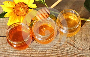 Honey in a glass jar with flowers on the wooden floor.