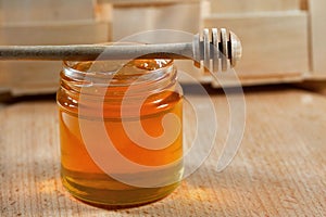 Honey in a glass jar with a honey dipper on a wooden table, close-up