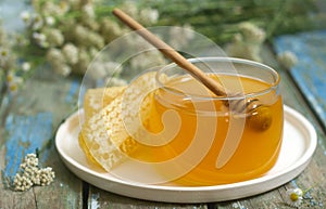 Honey in a glass jar and honey in honeycombs on an old wooden background