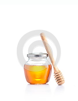 Honey in glass jar and wodden honey dipper leaning on the jar