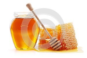 Honey in glass jar with wooden dipper and honeycombs