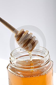 Honey in a glass jar with a wooden stirrer