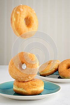 Honey glazed donuts falling on plate