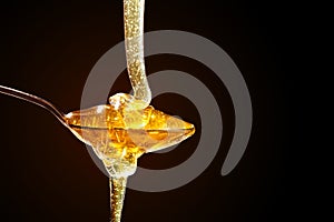 Honey with gold color flows down from a spoon, on a dark background. Healthy eating. Diet. Selective focus. Background