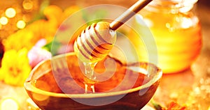 Honey. Healthy organic thick honey dripping from the honey dipper in wooden bowl. Sweet dessert