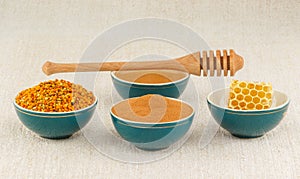Honey, honeycomb, pollen granules and cinnamon in bowls