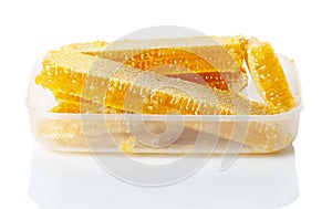 Honey in honeycombs in a plastic box on a white background