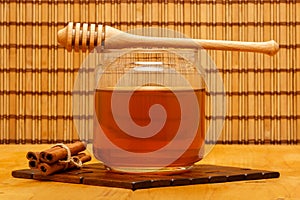Honey in jar with dipper and cinnamon bars