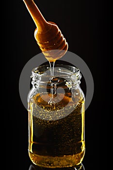 Honey jar with dipper and flowing honey