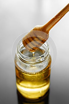 Honey jar with dipper and flowing honey