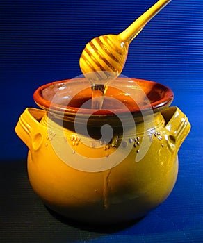 Honey jar with dipper and flowing honey