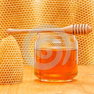 Honey in jar with dipper on honeycomb background