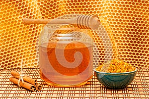 Honey in jar with dipper, honeycomb, cinnamon and