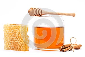 Honey in jar with dipper, honeycomb, cinnamon on isolated background