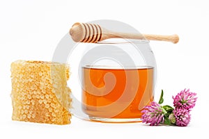 Honey in jar with dipper, honeycomb, flower on isolated background