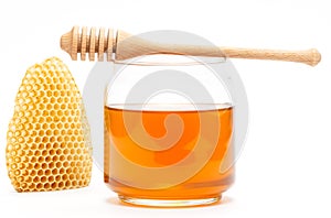 Honey in jar with dipper and honeycomb on isolated background