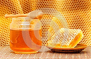 Honey in jar with dipper and honeycomb on mat