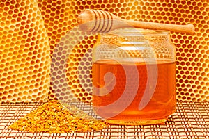 Honey in jar with dipper, honeycomb and pollen