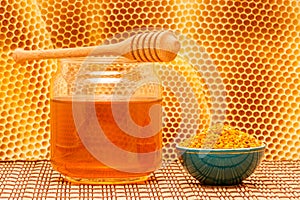 Honey in jar with dipper, honeycomb and pollen in