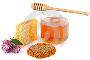 Honey in jar with dipper, honeycomb, pollen and flowers