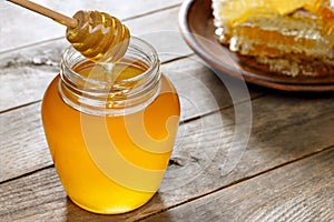 honey in jar with dipper and honeycomb on wooden table